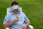 Blindfolded man in a long chair holding a glass of wine